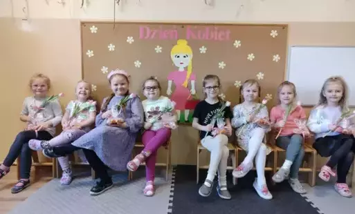 dziewczynki dumnie siedzą na krześle z kwiatkiem w ręku